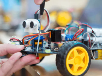 An image of a hand fixing a small toy robot