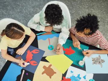 Three children creating ocean animal paper crafts