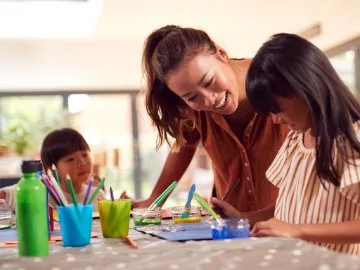 A woman and two children work on art projects