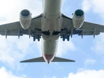 An aircraft flying low overhead, with sky in the background