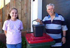 A grandfather and granddaughter next to a bin with a FOGO caddy on top