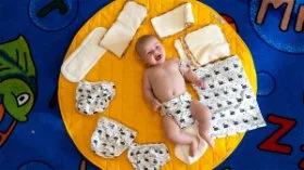 A baby on a rug surrounded by reusable nappy.