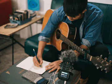 A musician writing a song while playing guitar